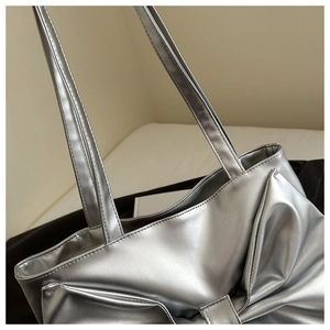 Detailed view of silver metallic tote bag with large decorative bow and dual straps