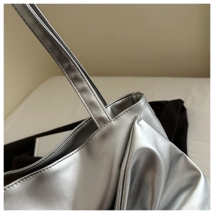Detail showing high-quality stitching and silver metallic leather texture of the tote bag