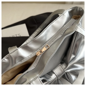 Close-up of metallic silver tote bag zipper with large decorative bow and shiny texture