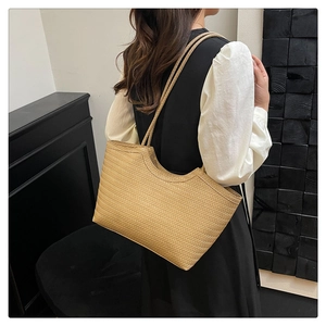 Detail of hand-woven straw tote bag with delicate wave texture and cord handles