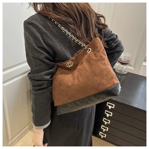 Detail of a quilted tote bag in brown suede with chain straps on a female model