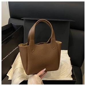 Detail of brown litchi pattern leather handbag on premium silk and black gift box