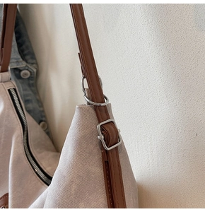 Detail of adjustable leather strap and silver metal buckle on beige canvas tote bag
