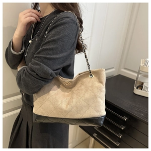 Detalle del bolso tote acolchado beige con cadena y herrajes dorados en la modelo