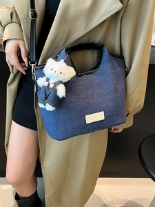 Denim handbag with black leather handles and cute white plush bear charm accessory