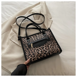 Top view of leopard print tote bag with black leather trim on minimalist beige bedding