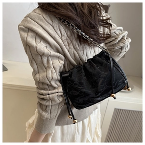 Détail du sac seau noir plissé avec bandoulière chaîne dorée et cordon à perles métal
