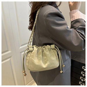Détail du sac nuage vert sauge avec glands à cordon et bandoulière en chaîne dorée