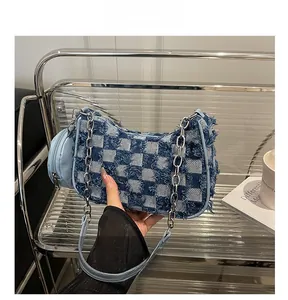 Detail of denim checkered shoulder bag with frayed edges and mini round coin purse charm
