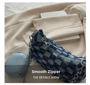 Close-up of blue checkerboard denim handbag with distressed frayed edges and silver chain