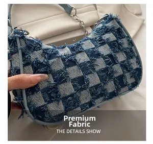 Detail of denim checkered shoulder bag with frayed edges and blue leather strap
