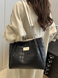 Black quilted nylon tote bag with leather trim and silver chain straps shown on a model