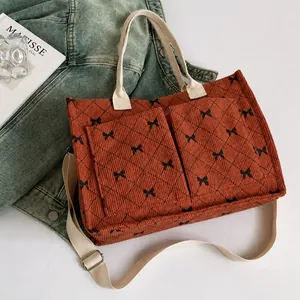 Detail view of corduroy tote bag with bow texture, functional pockets and beige straps