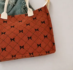 Macro detail of brown corduroy tote with quilted patterns and small black bow prints