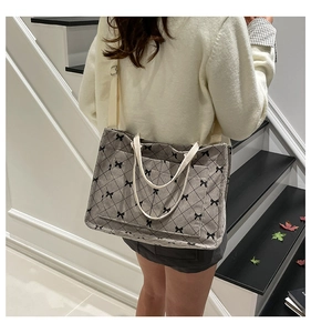Detail of grey corduroy tote bag with bow prints and beige straps shown on model