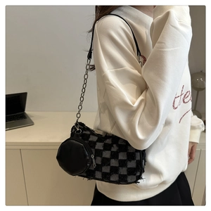 Detail view of plush checkered shoulder bag with silver chain strap and small round pouch