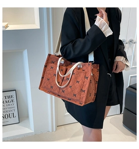 Detail of caramel tote bag with black bow lattice pattern and corduroy texture on model