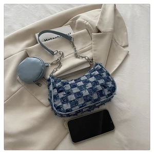 Detailed close-up of blue plaid tweed shoulder bag with fringe trim and mini coin purse