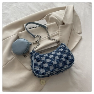 Detail of blue denim checkerboard shoulder bag with silver chain and mini pouch