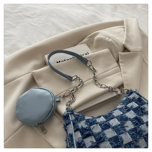 Detail of blue checkerboard denim handbag with frayed edges and metal chain strap