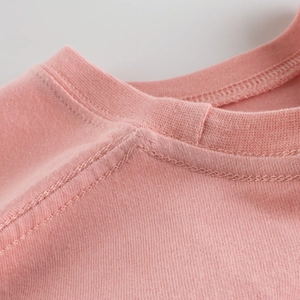 Gros plan d'un t-shirt rose pour enfant en maille montrant les coutures de l'encolure
