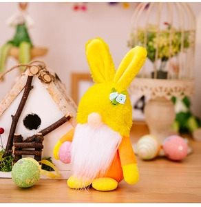 Détail d'un gnome de Pâques en peluche avec barbe blanche tenant un œuf à pois roses