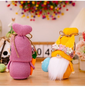 Detailed close-up of knitted Easter gnomes with carrot and egg on a wooden table