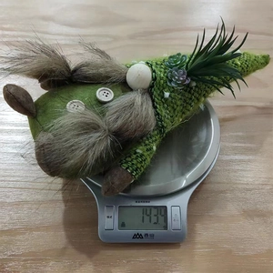 Close-up showing the weight of a green knitted succulent gnome plush on a digital scale