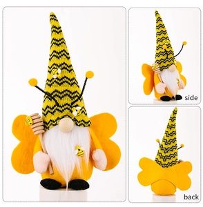 Detail view of a bee gnome plush with striped hat, felt wings, and honey stirrer