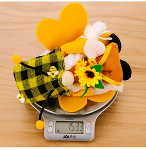 Close-up of bumblebee gnome with sunflower and yellow black plaid hat on digital scale