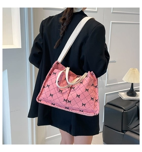 Close-up of pink tote bag with black bow print and textured fabric on a model
