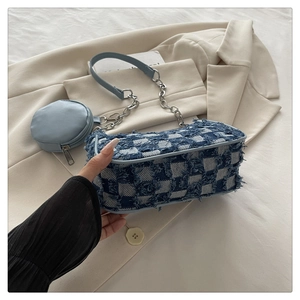 Detail of blue plaid canvas tote with silver chain and mini pouch on beige blazer