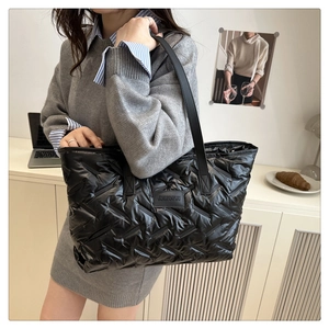 Gros plan du sac cabas matelassé noir brillant avec logo et texture plissée naturelle