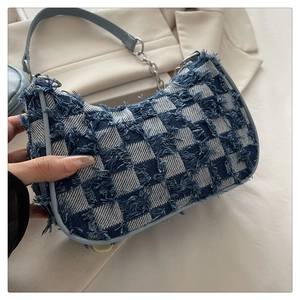 Detail of blue checkerboard denim bag showing frayed edges and silver chain strap