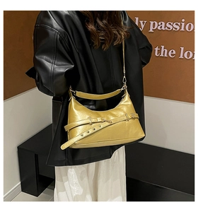 Detail of a metallic gold hobo bag with retro buckle, styled on a model in a leather jacket