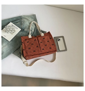 Detail of red corduroy tote bag featuring black bow patterns and front pockets