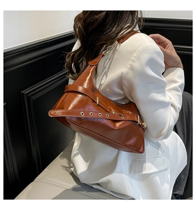 Detail of vintage brown shoulder bag with shiny oil-wax leather texture and belt buckle