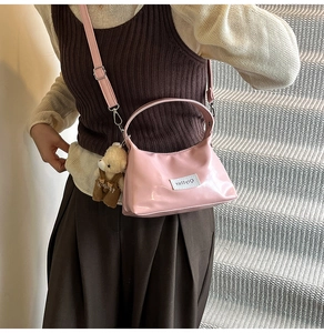 Detail of pink glossy crossbody bag with cute teddy bear charm and adjustable strap