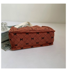 Detail of tan corduroy tote bag with black bow lattice pattern and white fabric handles