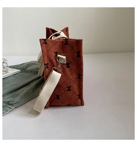 Detailed side view of rust red corduroy tote bag with diamond stitching and bow pattern