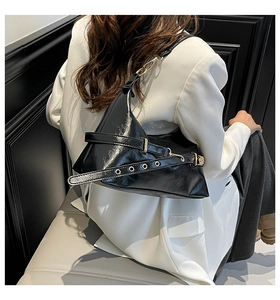 Polished black triangular underarm bag with glossy finish and golden metal eyelets
