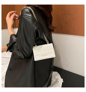 Dettaglio della borsa squadrata bianca plissettata con catena dorata e texture in PU