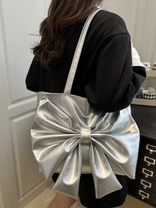 Silver metallic tote bag with large bow design shown on model for daily street style