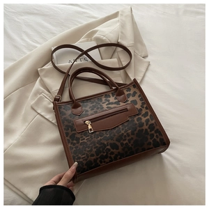 Close-up of leopard print handbag with leather trim and shoulder strap on a blazer