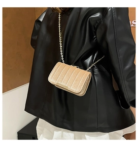Detail of champagne gold velvet crossbody bag with vertical pleats and chain strap