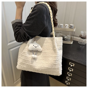 Close-up of white woven tote bag with braided strap and cute plush cloud charm detail