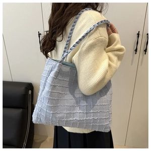Vue latérale d'un sac cabas en tweed bleu clair avec bandoulière tissée sur un mannequin