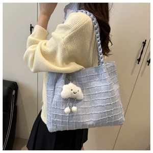 Detail of light blue woven tote bag with chunky braided strap and white cloud charm