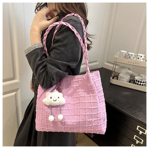 Detail of pink waffle texture handbag with braided handle and cute cloud pendant charm