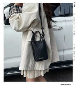 Détail d'un mini sac cabas noir tressé avec bandoulière porté par un mannequin